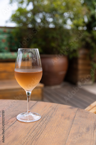 Glass of orange wine on wood table in outdoor patio 