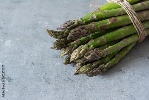 Raw green asparagus on a blue background. Raw food concept, place for copy space.