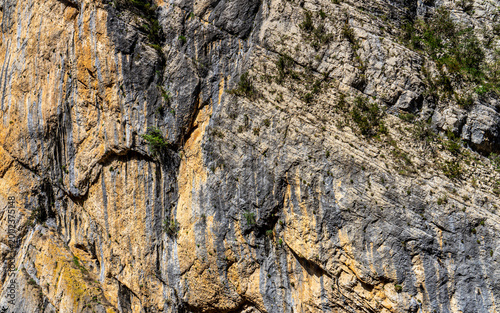 Dramatic limestone cliff face with golden orange and grey rock textures