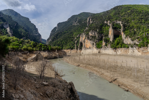 Dried reservoir riverbed with dramatic limestone cliffs and green mountains