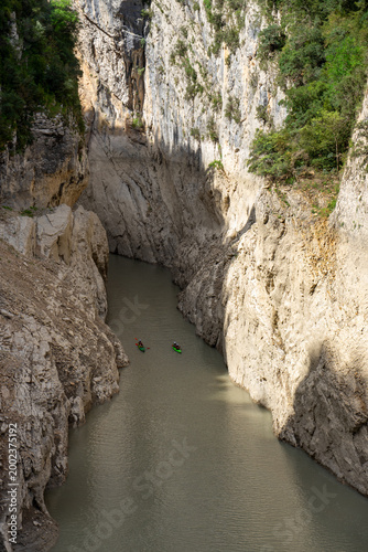 Kayakers paddling through dramatic limestone canyon with turquoise river