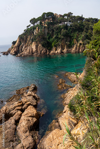 Rocky Mediterranean coastline with turquoise water and clifftop villas