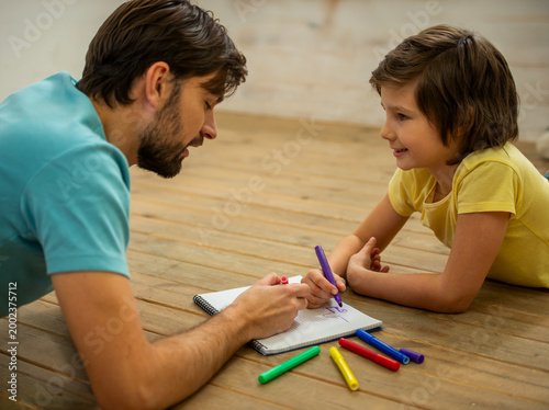 Father teaching child drawing.