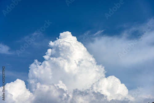 Cumulus white clouds bodies towering in clear blue sky background.