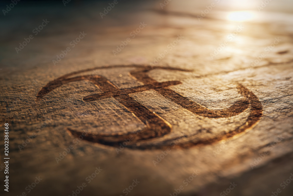 Fototapeta premium Sunlit close-up of a rustic anchor symbol carved into aged wood, highlighting texture and nautical design elements with warm natural lighting effects