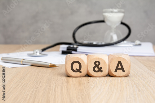 Q and A text on wooden blocks with stethoscope and hourglass