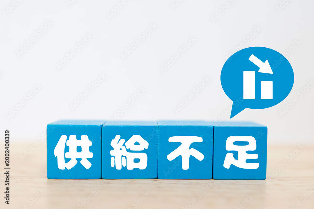 Fototapeta premium 供給不足をイメージする下降グラフ。青いブロック文字で「供給不足」と表示。コピースペースあり
