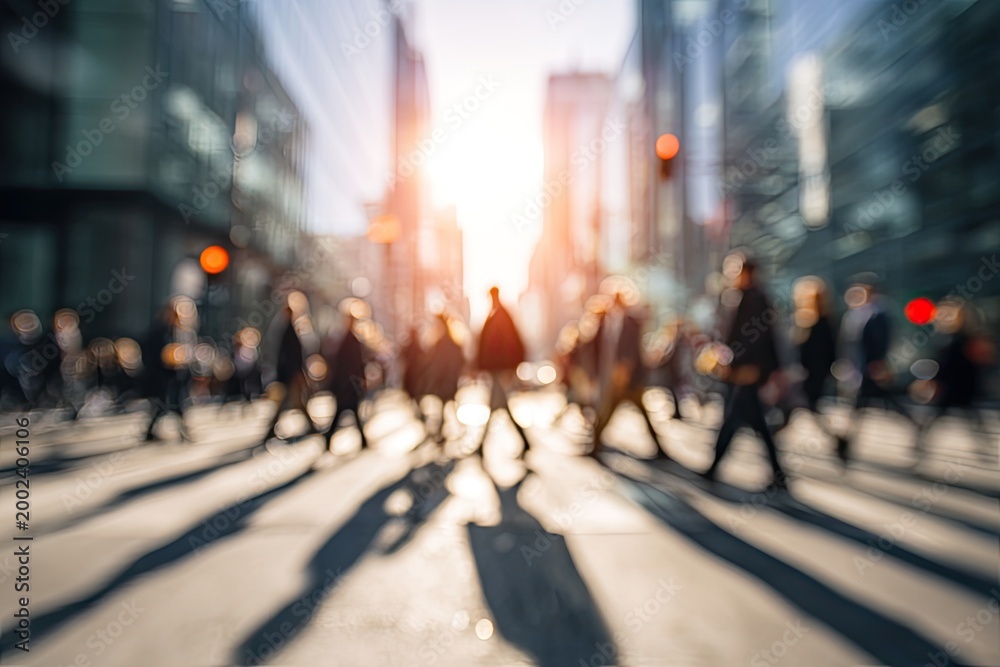 Obraz premium A blurred, sun-drenched cityscape captures the motion of pedestrians crossing a busy street, evoking a sense of urban energy and fleeting moments.