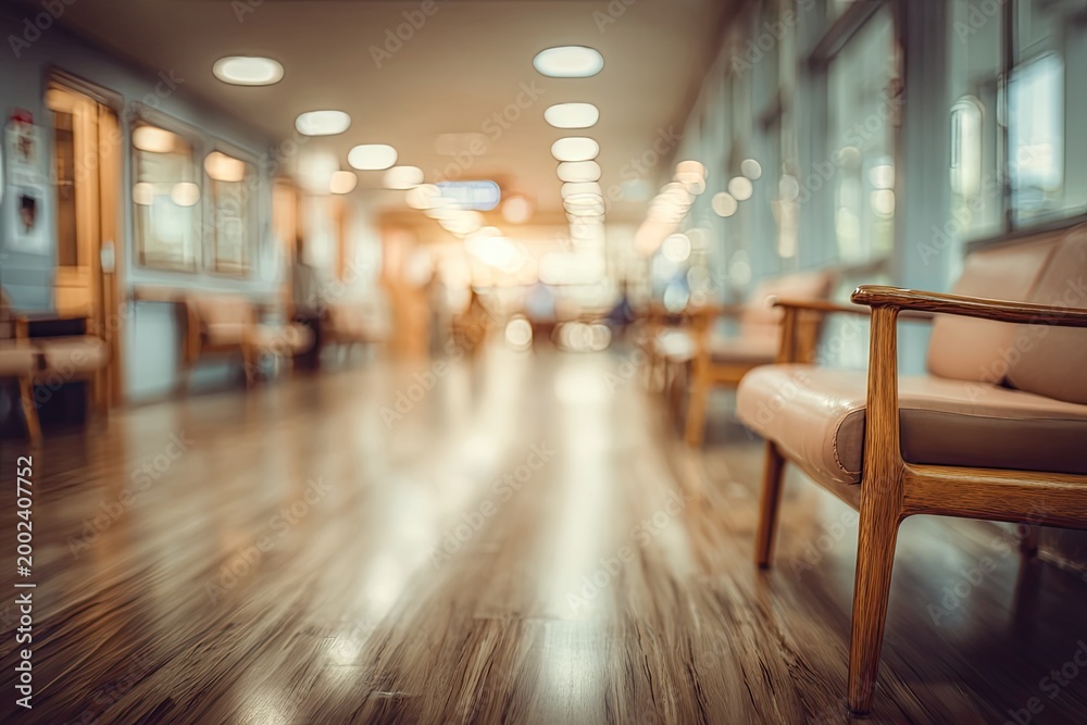Fototapeta premium A softly lit hospital hallway stretches into the distance, featuring wooden seating and a polished floor, creating a sense of calm and quiet anticipation.