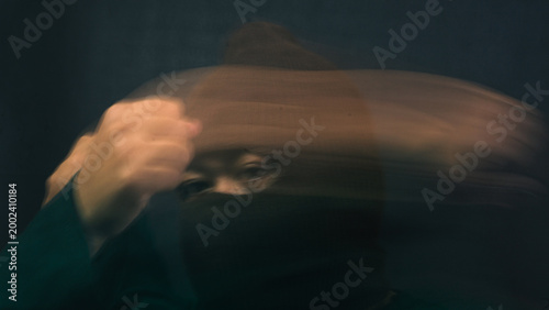 Foto A mysterious male figure wearing a brown balaclava is heavily obscured by extreme horizontal motion blur from his hand sweeping across his face