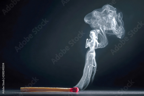 A creative visual of a burnt matchstick with smoke rising and swirling into the shape of a dancing woman against a dark background for artistic concept photography