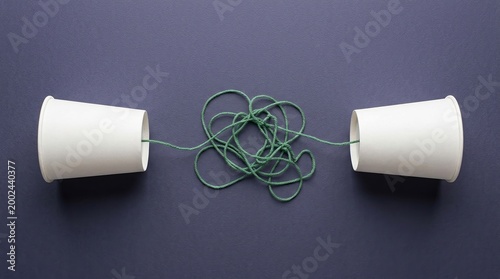 Communication misunderstanding problem confusion tangled connection paper cup phone concept representing business challenges, dialogue breakdown, and complex speech barriers.