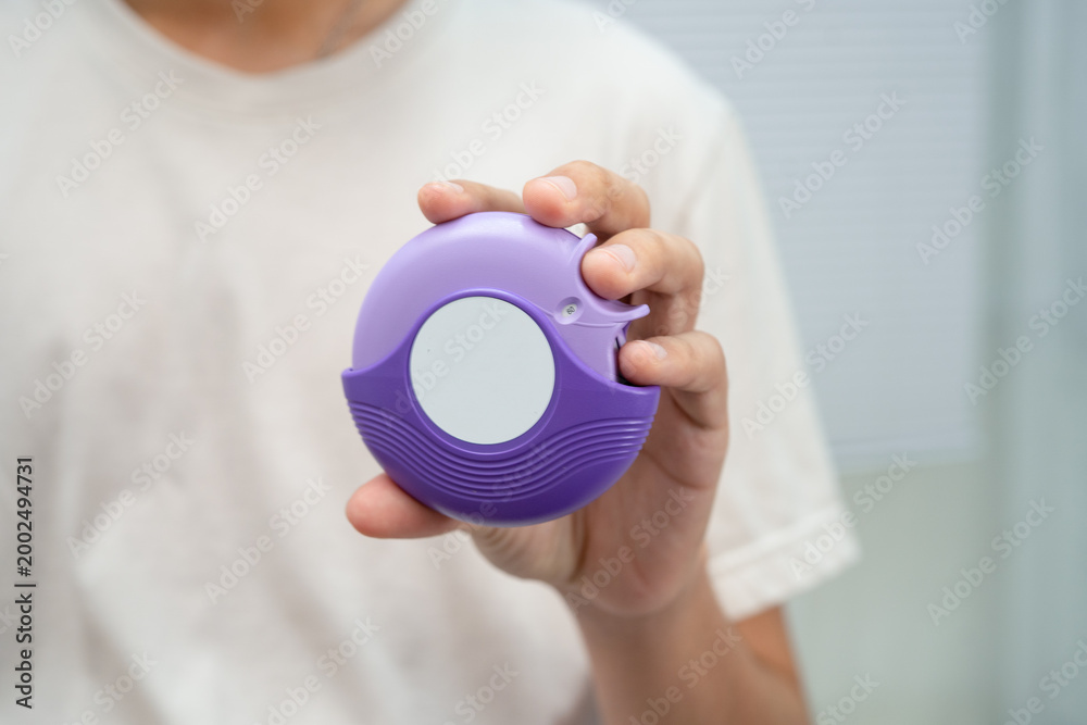Fototapeta premium Asthma and chronic obstructive pulmonary disease COPD, Asian young man using metered dose inhaler MDI.