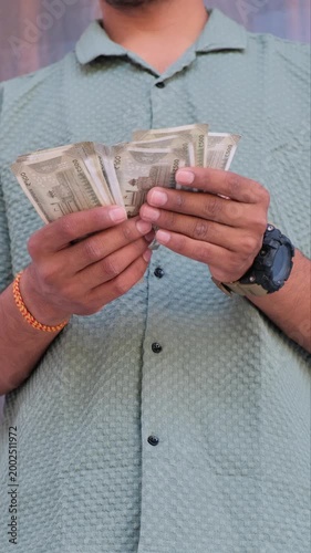 Close up of a man counting 500 rupee Indian currency notes outdoors