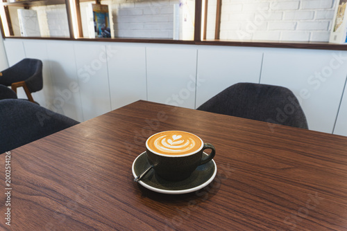 Hot Coffee Latte with Heart Latte Art on a Wooden Table in a Modern Cafe Interior Background