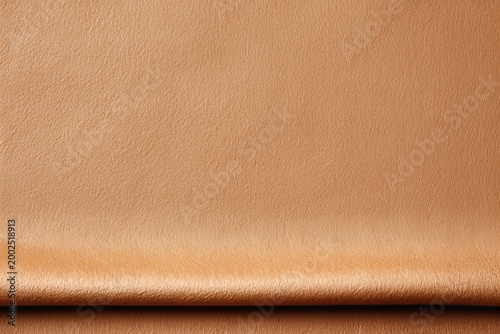 Soft camel tan suede fabric texture with elegant horizontal fold on smooth surface