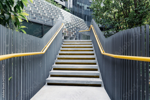 Modern Concrete Outdoor Staircase with Yellow Handrails and Grey Metal Fence in Urban Setting