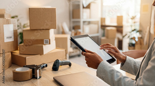 Foto E-commerce small business owner managing online orders and inventory with a digital tablet amidst shipping boxes