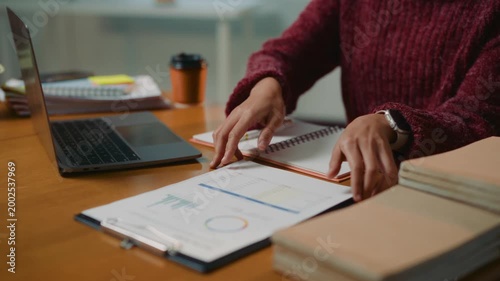 Young Asian entrepreneur happily checking financial data on a clipboard. Businesswoman working late at her desk on a new project