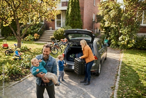 Happy Family Loading Luggage into Car Trunk for Road Trip - Family Vacation and Lifestyle - Concept for Travel Insurance and Holiday