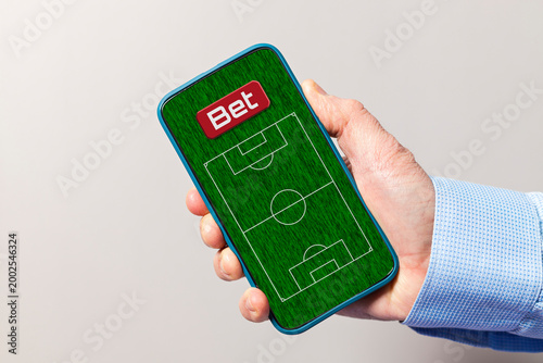 Hand holding smartphone showing soccer betting application
