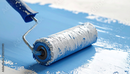Paint roller applying blue paint on a white surface closeup