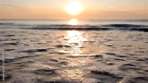 Cigarette butt on sandy beach at sunset, ocean waves and sun reflection