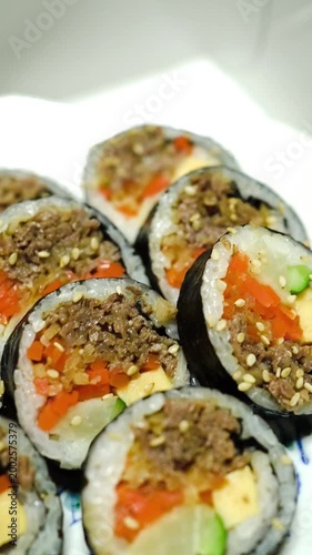 Close-up vertical video of delicious seaweed rice rolls (Kimbap) garnished with sesame seeds, perfect for healthy food content
