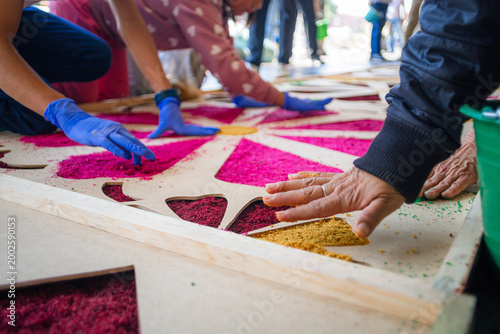 Bild auf Leinwand Close-up of artisan hands placing colored sawdust to create a monumental rug during Holy Week in Cholula, Puebla, Mexico