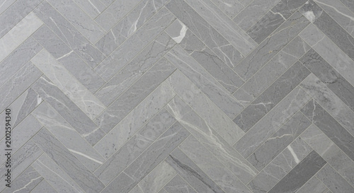 Elegant grey marble-effect ceramic tiles laid in a modern herringbone pattern perfect for luxurious flooring or sophisticated interior design backgrounds