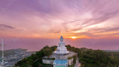 Aerial top panoramic sunset view great white marble Buddha statue sits serenely atop a lush Phuket peak top