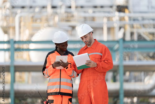 Oil refinery or Petroleum refinery. Gas pipeline network system at the industrial estate area. Petrochemical engineer in safety gear working, discussing of work at petrochemical industrial estate