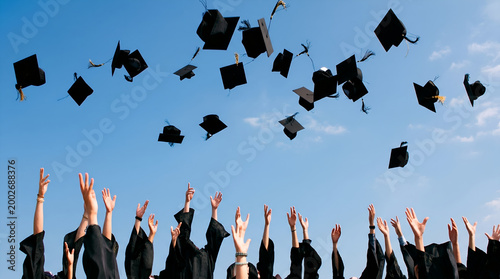 Group of university students throwing graduation caps in the air against blue sky