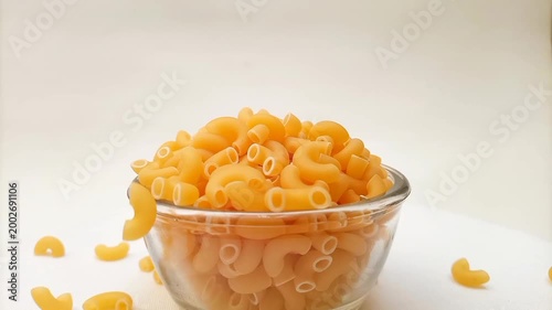 Elbow Macaroni Pasta Dropping in Glass Bowl on White Background, Uncooked Elbow Macaroni Pasta Ingredient