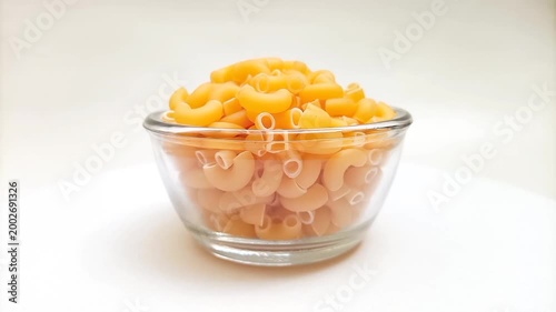 Elbow Macaroni Pasta in Glass Bowl Rotating on White Background, Uncooked Elbow Macaroni Pasta Ingredient
