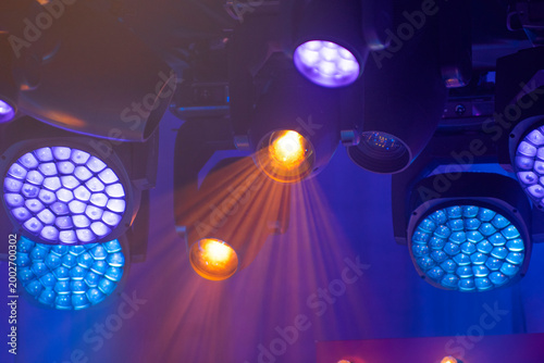 Multiple colorful stage LED spotlights with bright beams and haze with copy space