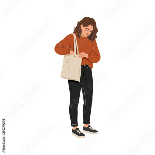 Woman holding a tote bag while standing outdoors looking down