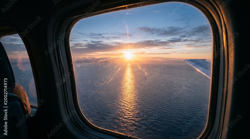 Fototapeta premium Serene vista from an airplane window, capturing a magnificent sunset over the vast expanse of the ocean, with warm golden light reflecting beautifully on the tranquil water