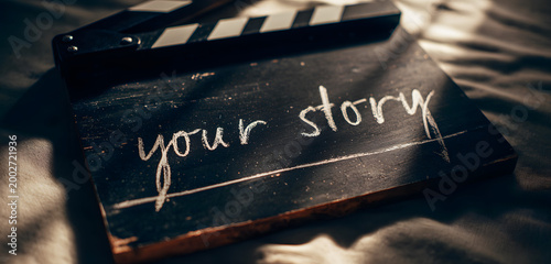 A black film clapboard with white chalk text reading your story is a symbol of filmmaking and storytelling.