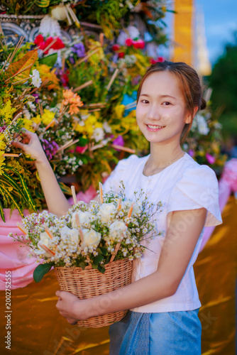 Asian woman in Lanna dress offering flowers at Sai Khan Dok tradition during Inthakin City Pillar Festival at Wat Chedi Luang Temple in Chiang Mai Thailand for travel and culture concept background