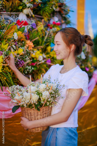 Asian woman in Lanna dress offering flowers at Sai Khan Dok tradition during Inthakin City Pillar Festival at Wat Chedi Luang Temple in Chiang Mai Thailand for travel and culture concept background