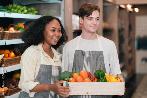 Fresh produce market smiling couple grocery store vegetable crate apron organic food retail worker fresh fruit fresh vegetable indoor market