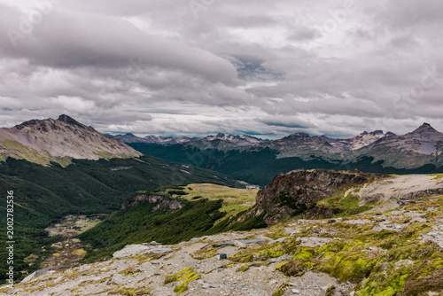 Vast panoramic view of green valleys and distant mountain ranges under a cloudy sky