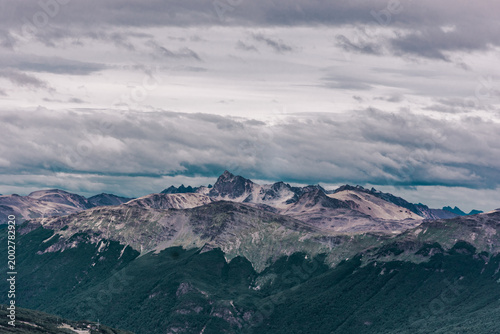 Stunning landscape of dark mountain peaks and deep forests under a heavy overcast sk