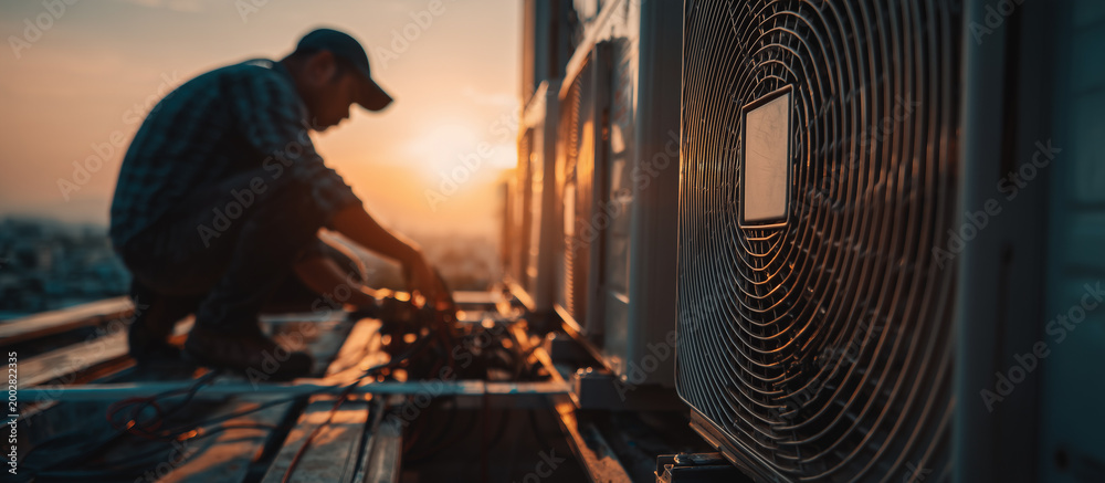 Fototapeta premium close up a technician repairs an modern outdoor air conditioning unit on a rooftop