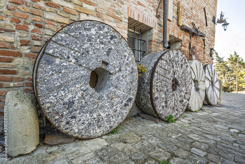 Foto Old stone millstones displayed against a rustic wall in the village of Mondaino,