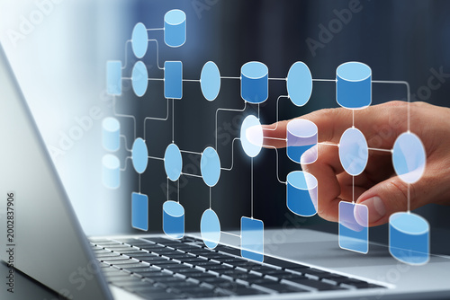 Data processing system. Data collection and transformation within network. Businessman tapping data flow diagram on laptop keyboard.
