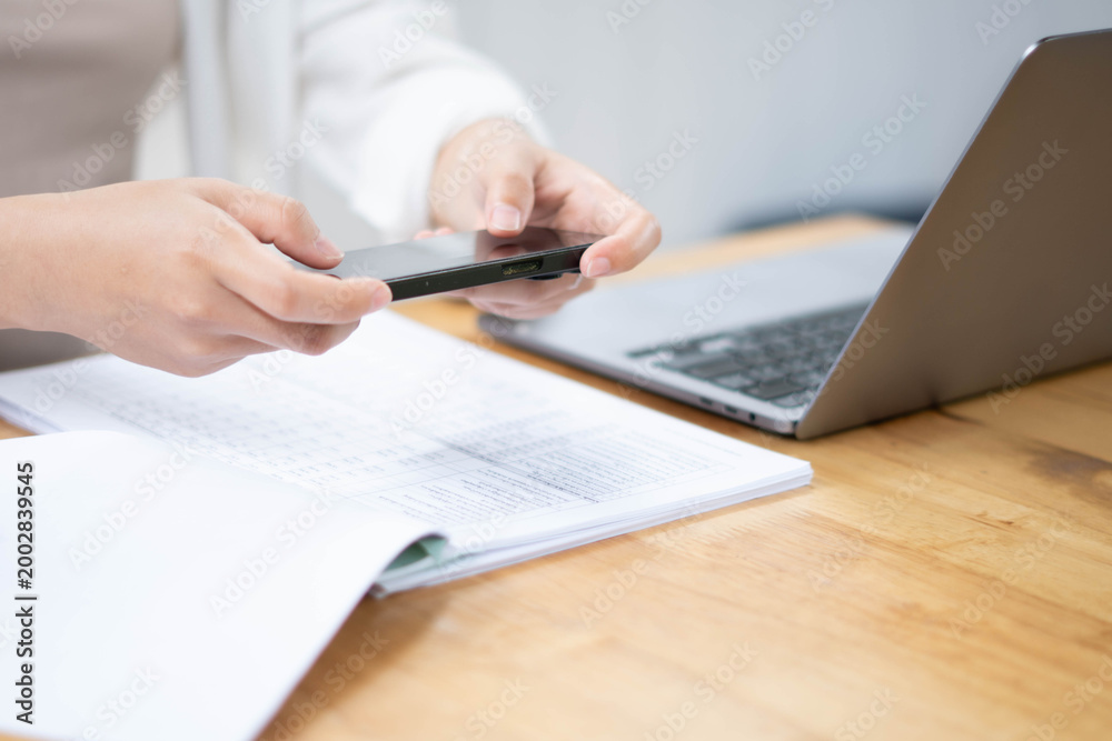 Fototapeta premium Businesswoman Using Smartphone While Reviewing Documents at Desk