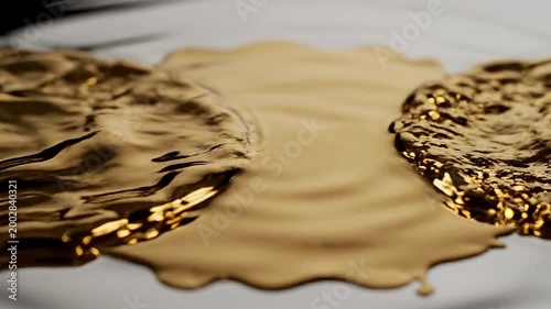 Golden liquid spills across a white surface in a messy video scene