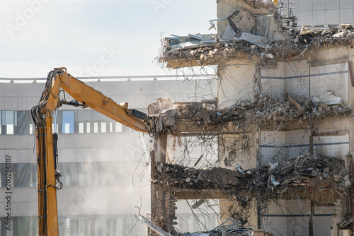 Construction site, demolition of reinforced concrete structure, gutting and renovation, hydraulic hammer dismantles building, caterpillar excavator machine